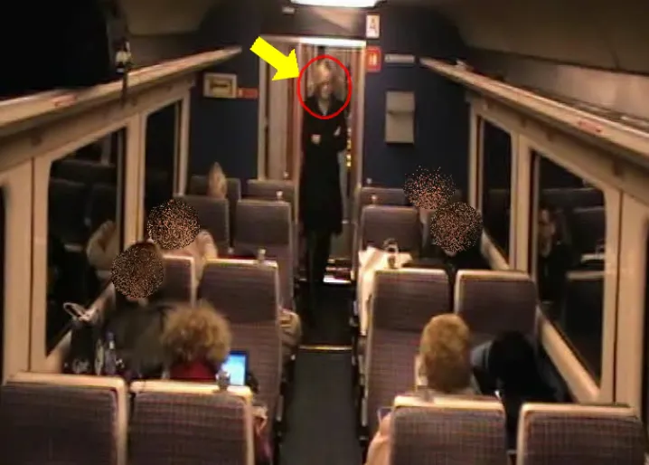 CCTV still inside a train carriage with the faces of seated passengers blurred out.