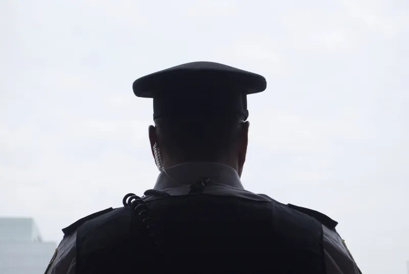 A police officer in uniform collecting video evidence from the scene of crime.