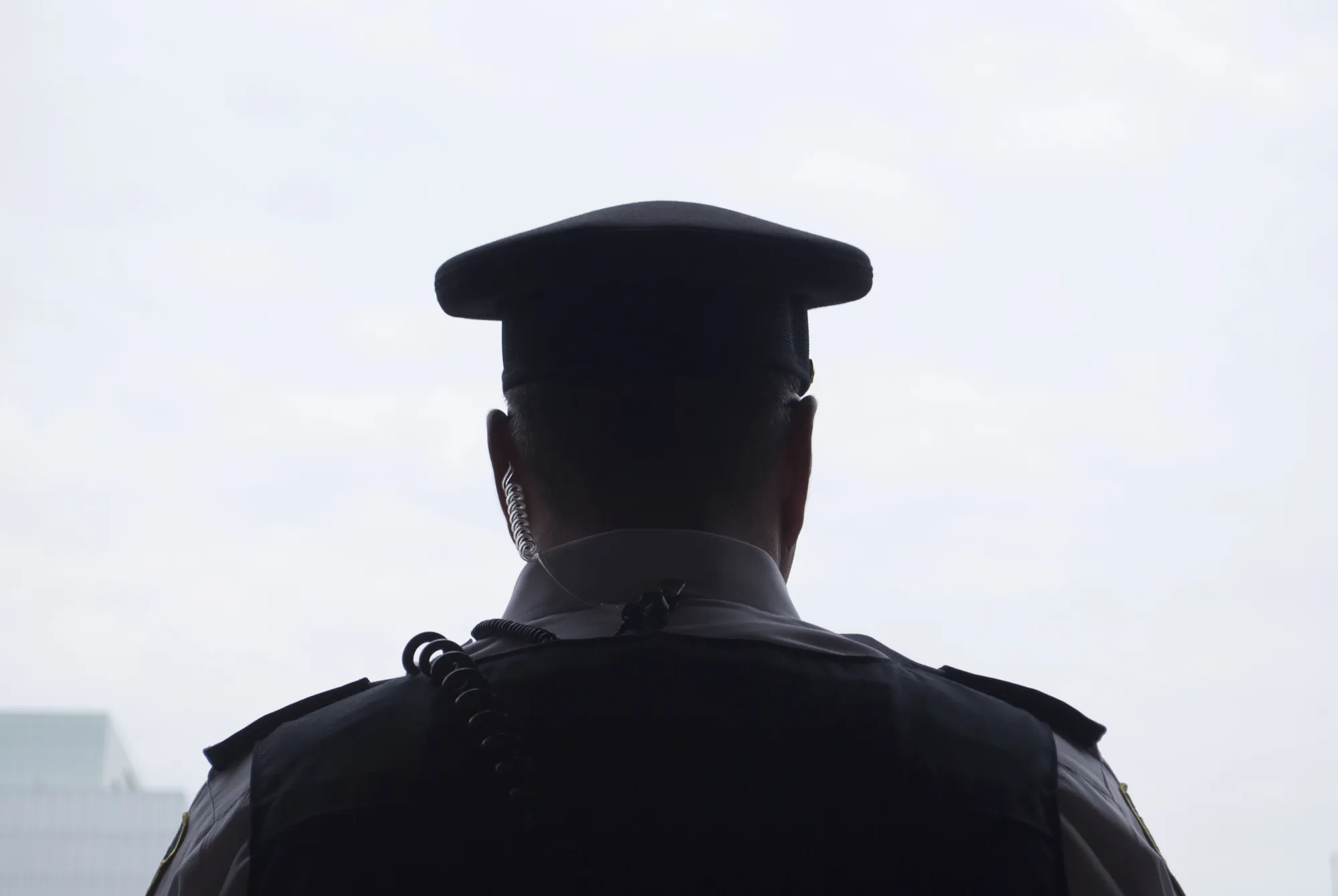 A police officer in uniform collecting video evidence from the scene of crime.